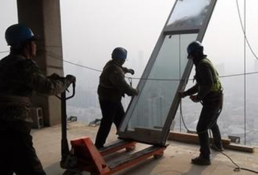 工人用手動(dòng)液壓搬運(yùn)車(chē)運(yùn)輸玻璃幕墻